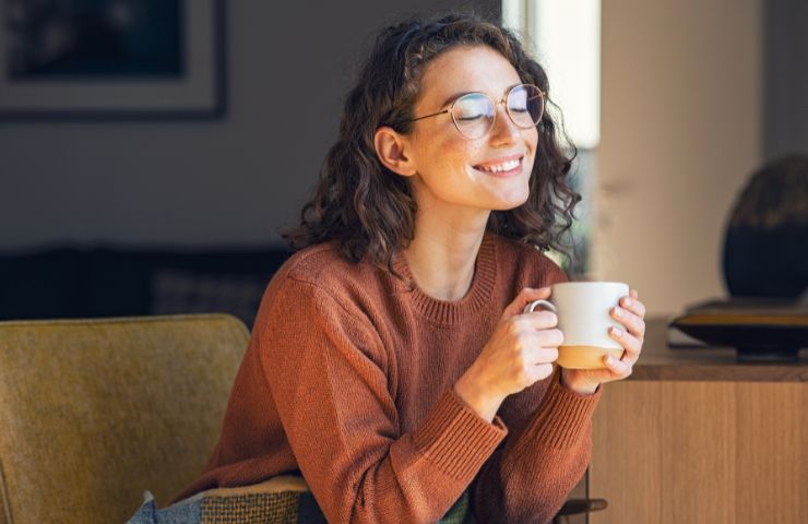 donna sorridente che beve una tazza di caffè